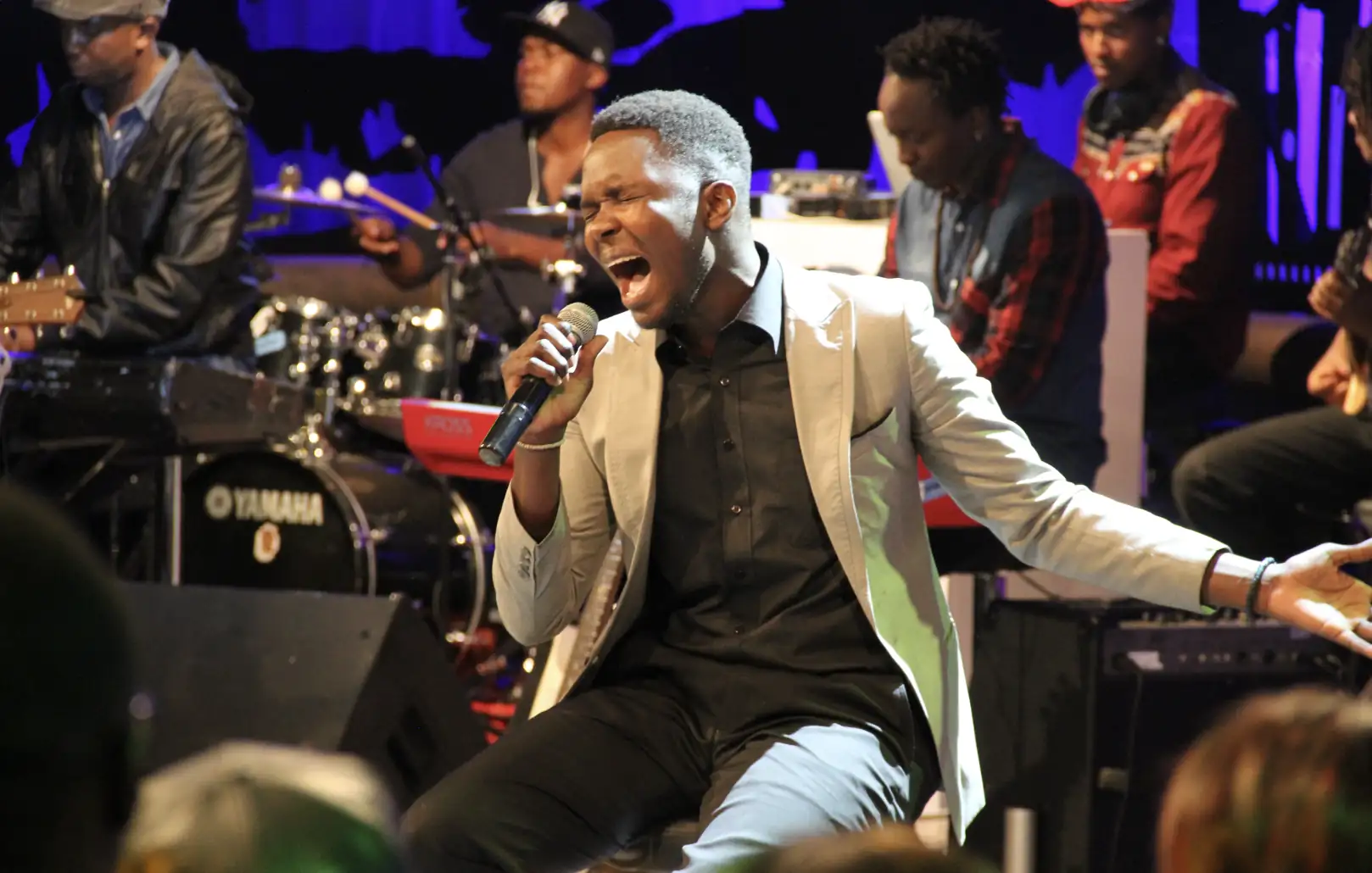 Male artist singing passionately on stage with a live band